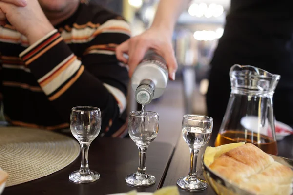 Официантка наполняет стаканы водки — стоковое фото