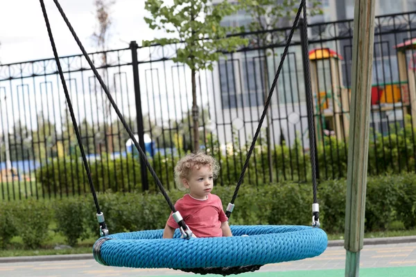 Niño rizado en swing — Foto de Stock
