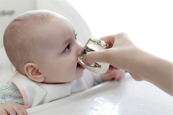 Bebé de 6 meses bebe agua de un biberón, acostado en la cama. bebe feliz y  alegre