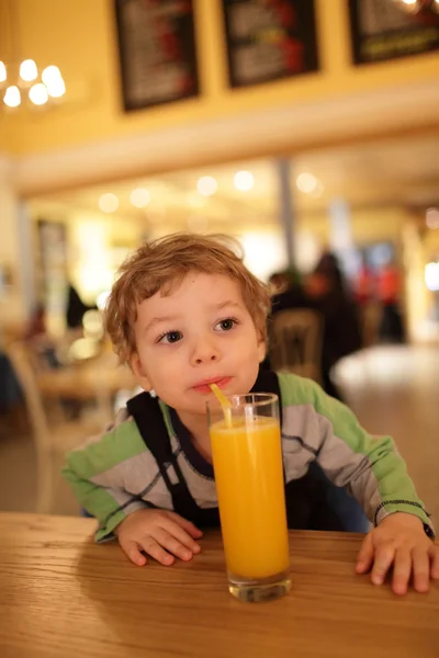 Dítě pije pomerančovou šťávu — Stock fotografie