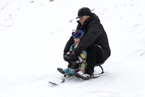 Grootvader met kleinzoon rit slee — Stockfoto