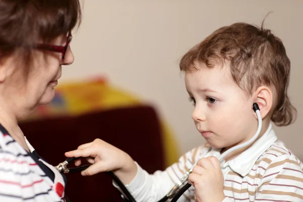 Çocuk stetoskop kullanarak büyükanne ele alıyor. — Stok fotoğraf