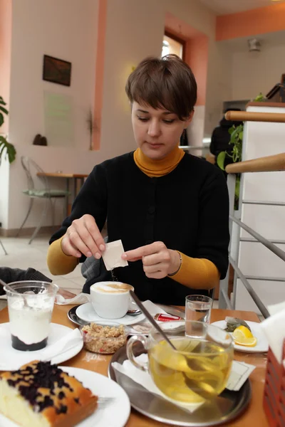 Woman pouring sugar into cup of coffee — Stock Photo, Image