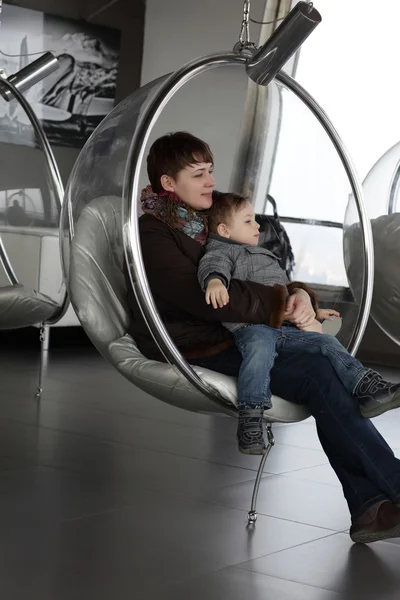 Family relaxes in glass chair — Stock Photo, Image