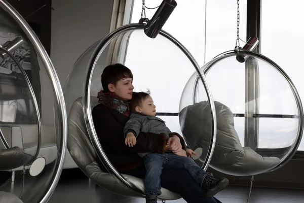 Mãe com filho relaxar na cadeira de vidro — Fotografia de Stock