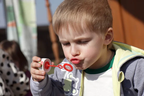 Kid blåser såpbubbla — Stockfoto