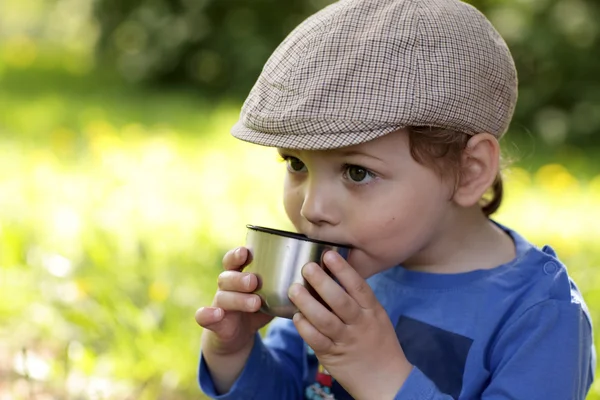 Мальчик пьет чай на открытом воздухе — стоковое фото