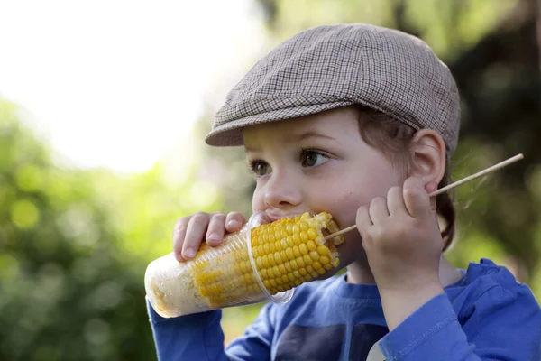 Chico hambriento comiendo maíz — Foto de Stock