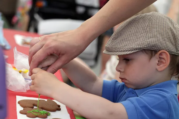 Kid painting gingerbread shapes — Stock Photo, Image