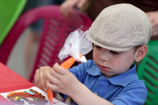 Kid decorating gingerbread shapes — Stock Photo, Image