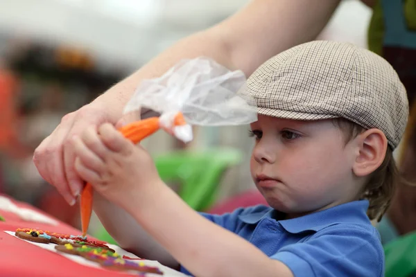 Moeder leren zoon decoratie van peperkoek — Stockfoto