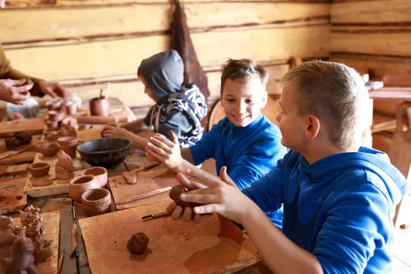 Three children make clay crafts in workshop