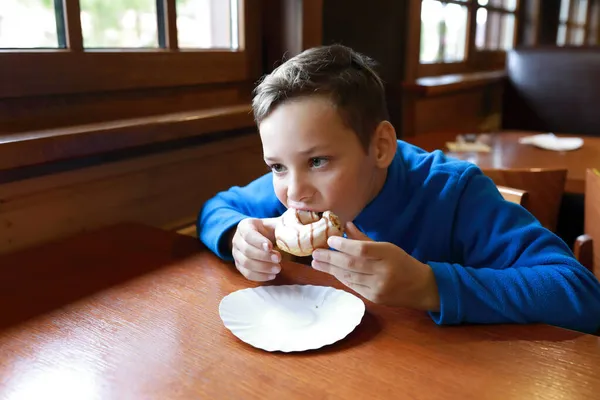 男の子はレストランのテーブルでドーナツを食べる — ストック写真