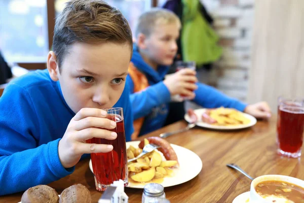 两个孩子在餐馆的饭桌上喝果汁 — 图库照片