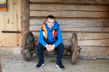 Kaliteli el arabasının ahşap tekerleğinde oturan çocuk.