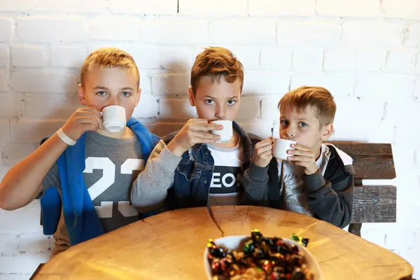 三个孩子在圆木桌边喝茶 — 图库照片
