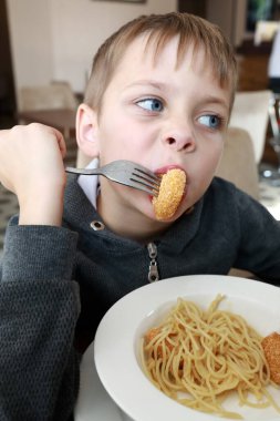 Çocuk restoranda makarna ve nugget yiyor.