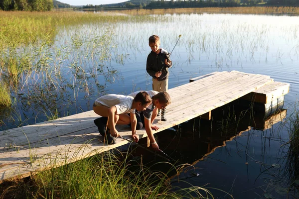 Yazın gölün kenarında oynayan üç çocuk, Karelia.