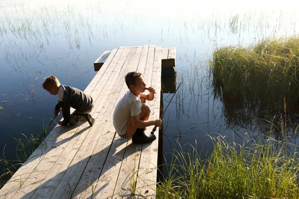 Brat Bawiący Się Latem Drewnianym Moście Nad Jeziorem Karelia — Zdjęcie stockowe