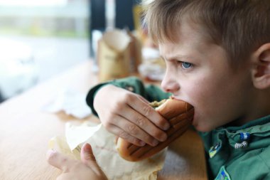 Restoranda sosisli yiyen çocuk portresi