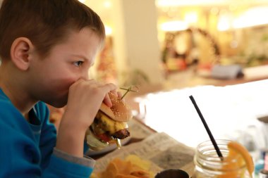 Geceleri barda hamburger yiyen çocuk.