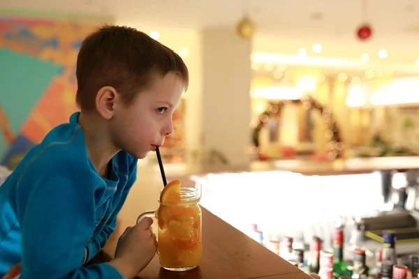 Child drinking lemonade with ice at bar of restaurant