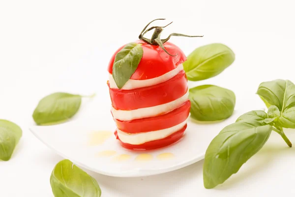 Fette di pomodoro e mozzarella decorate con foglie di basilico — Foto Stock