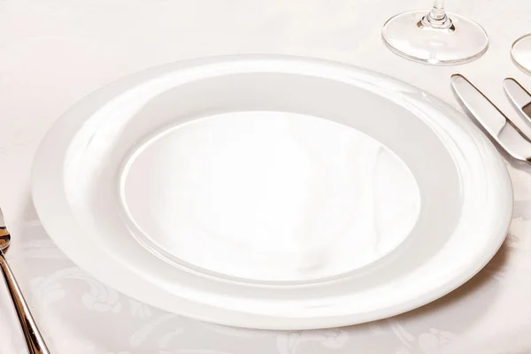 Белая пустая тарелка с вилкой и ножом — стоковое фото
