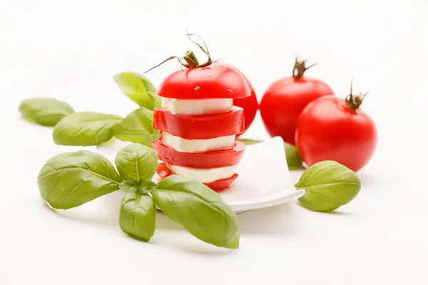 Rodajas de tomate y mozzarella decoradas con hojas de albahaca — Foto de Stock