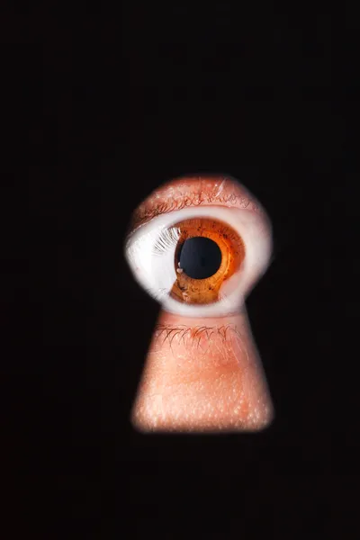 Eye looking through a keyhole — Stock Photo, Image