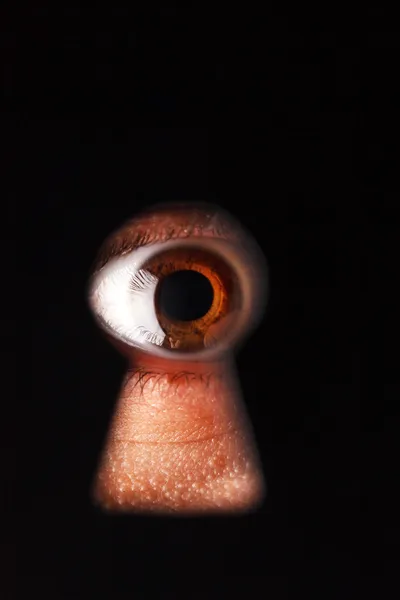 Eye looking through a keyhole — Stock Photo, Image