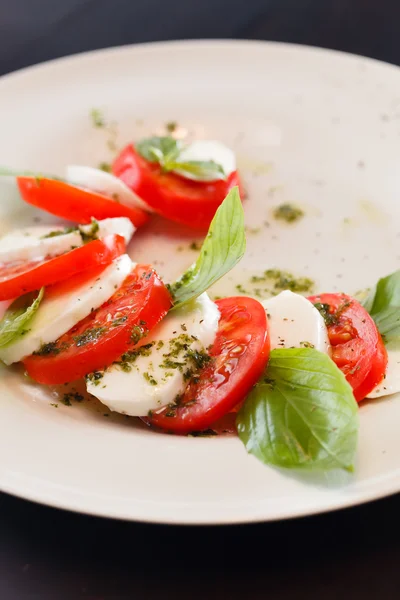 Tomaten und Mozzarella mit Basilikumblättern — Stockfoto