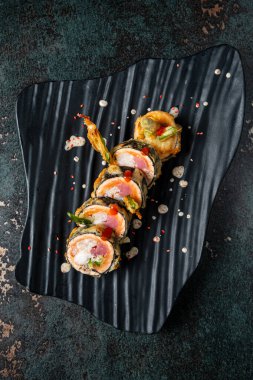 Siyah tabakta tempura sushi.