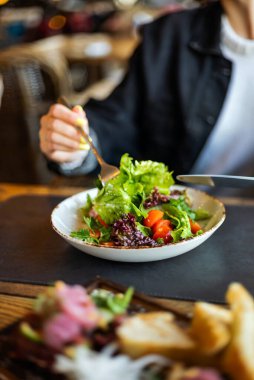 Restoranda salata yiyen bir kadın.