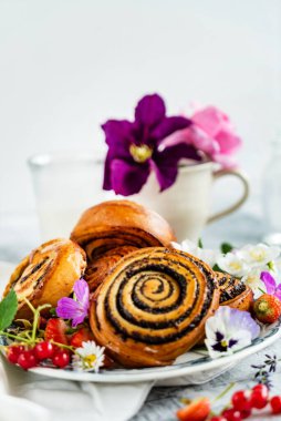 Taze pişmiş tarçınlı rulo ve çiçekler.