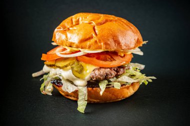Koyu arkaplanda lezzetli bir burger.