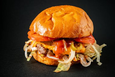Koyu arkaplanda lezzetli bir burger.