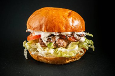 Koyu arkaplanda lezzetli bir burger.