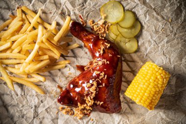 kızarmış tavuk budu mısır koçanı ve patates kızartması.