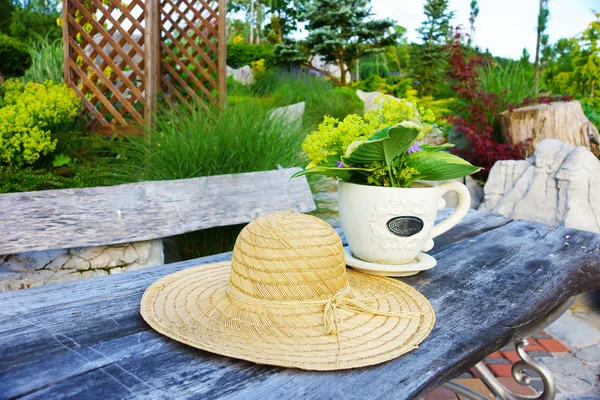 Hat and flowers on garden table — Stock Photo, Image