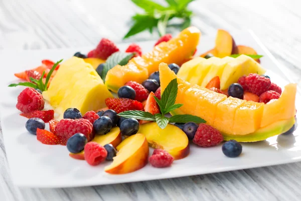 Different fruits and berries on a white plate — Stock Photo, Image