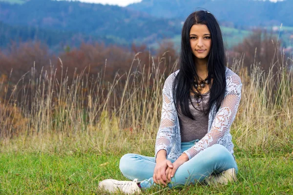 Mujer joven y bonita sentada en la hierba Imágenes de stock libres de derechos