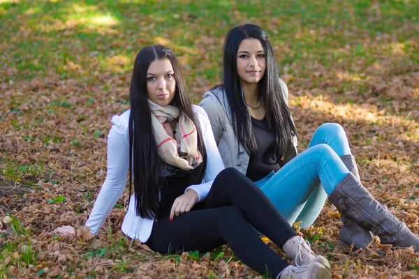 Duas meninas bonitas e felizes sentadas no parque em um dia de verão — Fotografia de Stock
