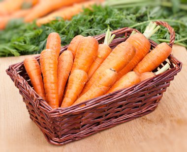 Fresh carrots in a basket on the table clipart