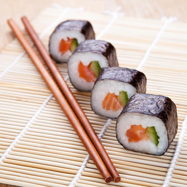 Deliciosos rollos de sushi fresco en la alfombra — Foto de Stock