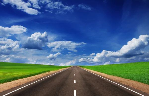 Asphalt road in green fields under beautiful sky — Stock Photo, Image