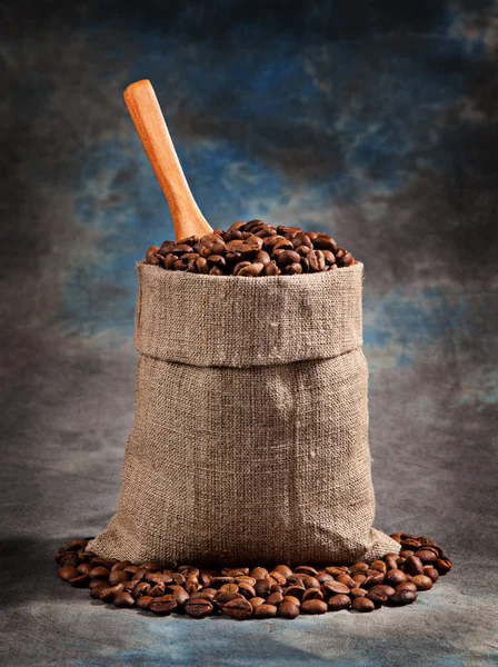 Granos de café tostados en una bolsa con una cucharada — Foto de Stock