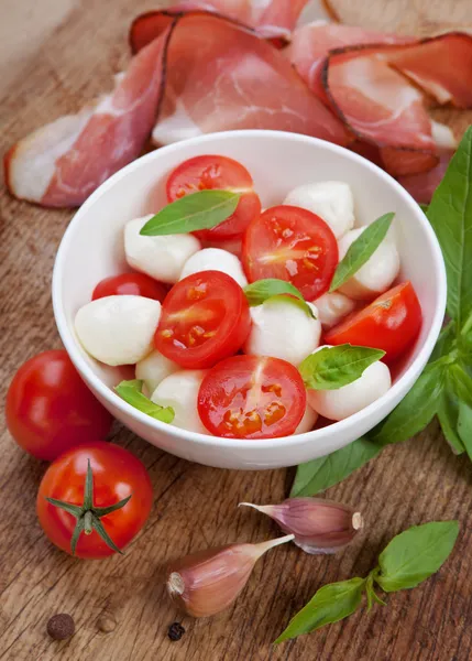 Салат капрезе с моцареллой, помидорами, базиликом на белой тарелке — стоковое фото
