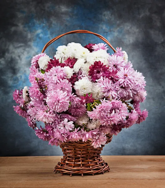 Chryzantémy v košíku na dřevěný stůl — Stock fotografie