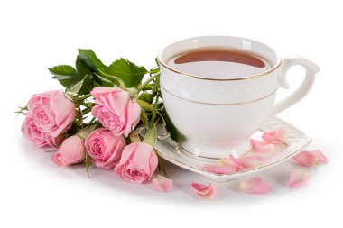 Beyaz arka planda izole edilmiş bir fincan çay ve pembe güller.